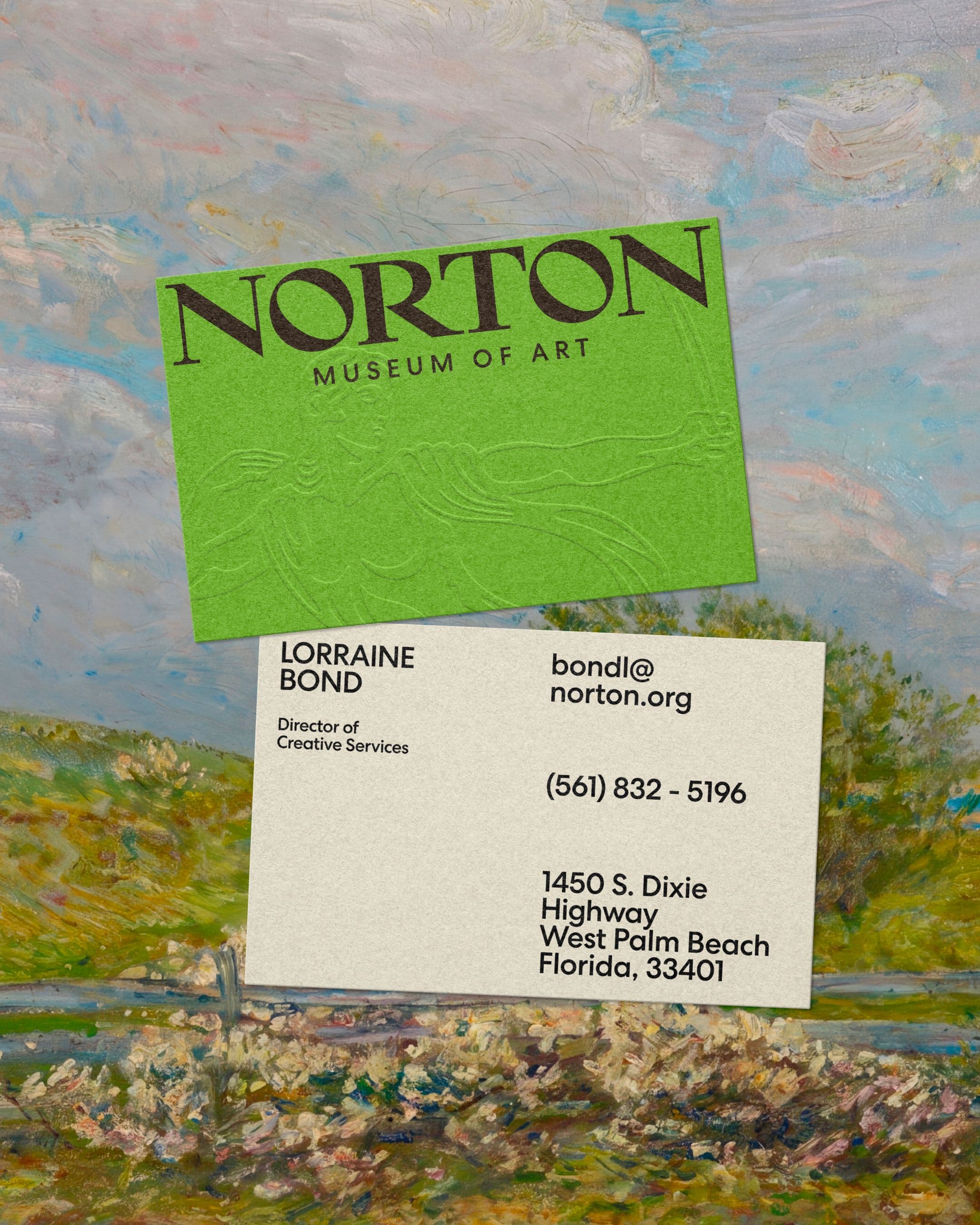 Front and back of a Norton Museum of Art business card, displayed against an Impressionist landscape painting. The front features the Norton logo on a bright green card with an embossed decorative motif, and the back shows staff contact details on a cream background.